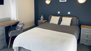 A bedroom with a bed, bedside tables, a desk, and a chair. - Blue Bell (Kettering)