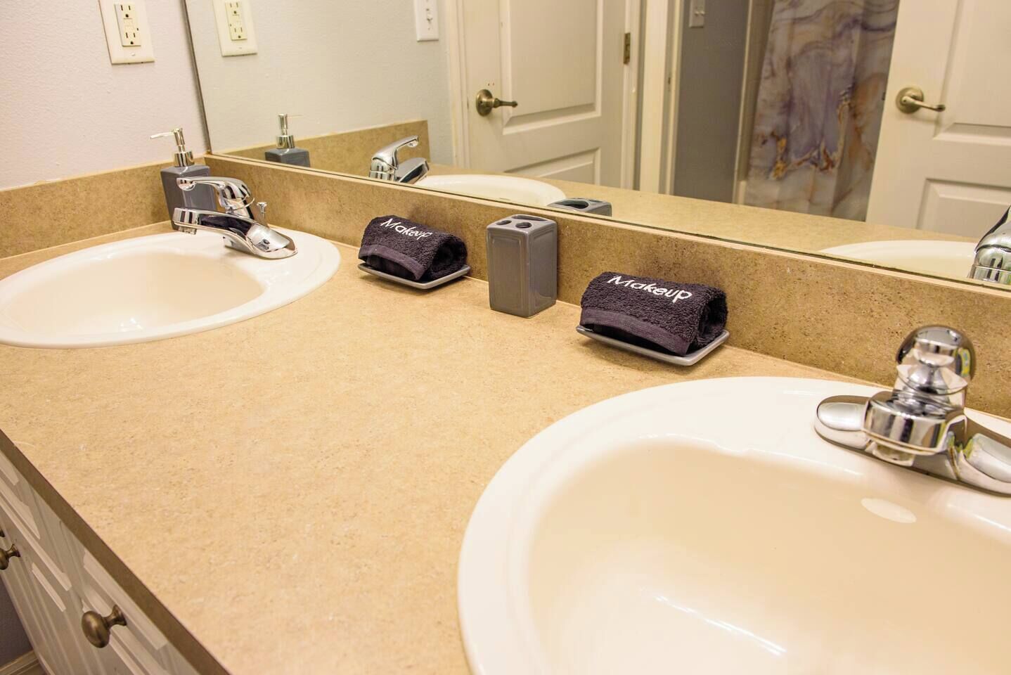 A bathroom with two sinks, a mirror, and a towel rack with a 'Makeup' towel.