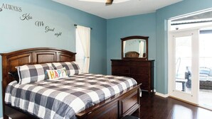 A bedroom with a wooden bed, a ceiling fan, a dresser, and a window with a view of the outdoors. - Relax in Heated Saltwater Pool w/ Screened Lanai (Lakeland)