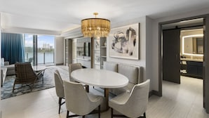 A modern dining area with a round table and six chairs, a chandelier, and artwork on the walls.