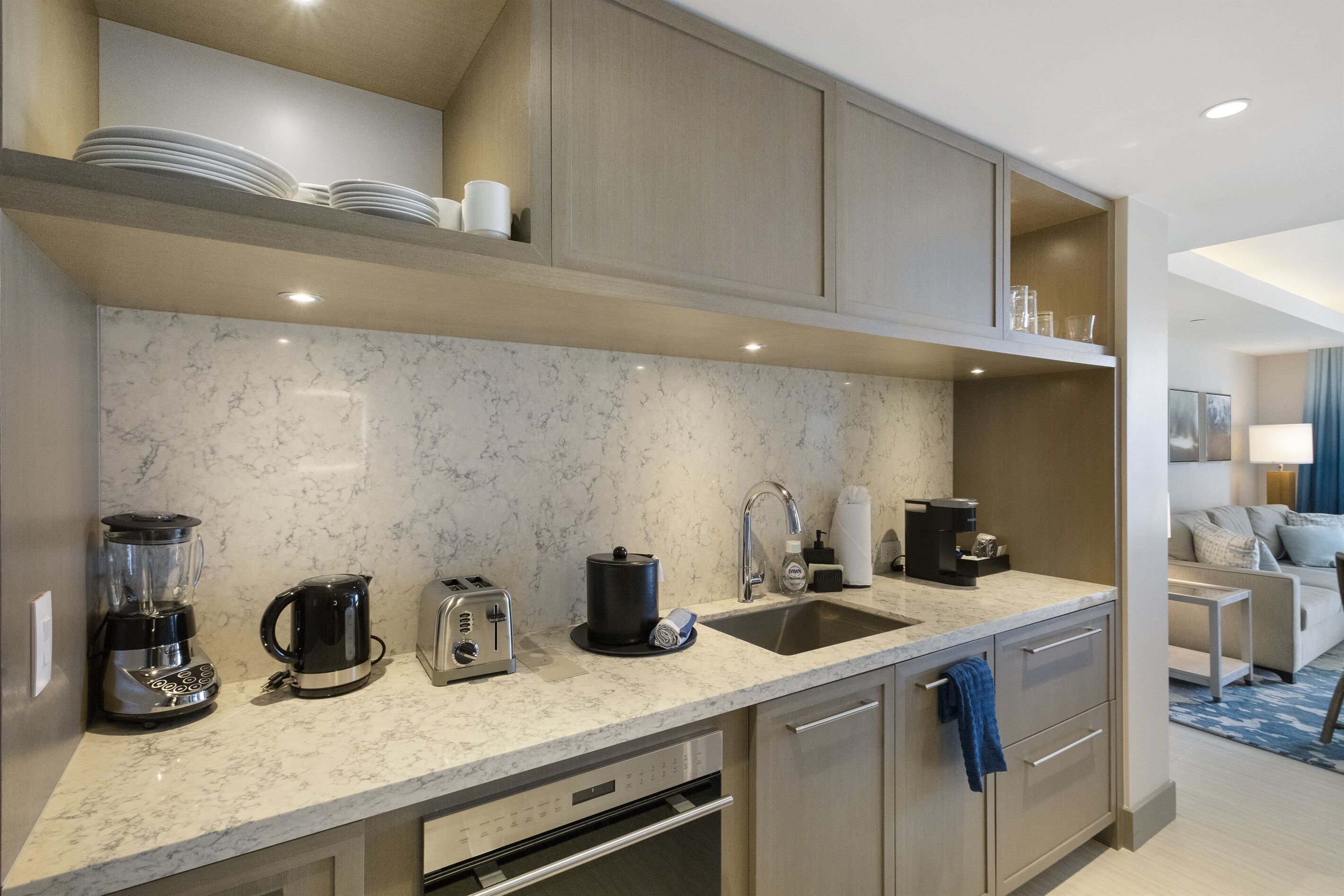 A modern kitchen with a marble countertop, built-in appliances, and a sink.