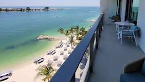 A balcony with a view of a beach and the sea.