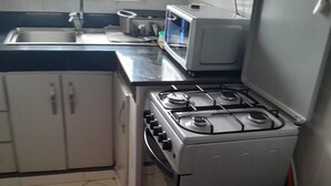 Une cuisine compacte équipée d’une cuisinière à gaz, d’un four à micro-ondes et d’un réfrigérateur.