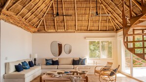 A spacious living room with a high thatched ceiling, a sofa set, a coffee table, and a dining area with chairs. - The Sweet Life Sayulita | Ocean Views (Sayulita)