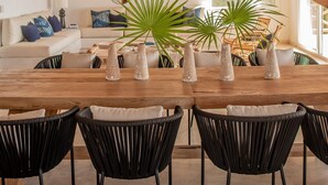 A dining area with a thatched roof, a wooden table, black chairs, and potted plants. - The Sweet Life Sayulita | Ocean Views (Sayulita)