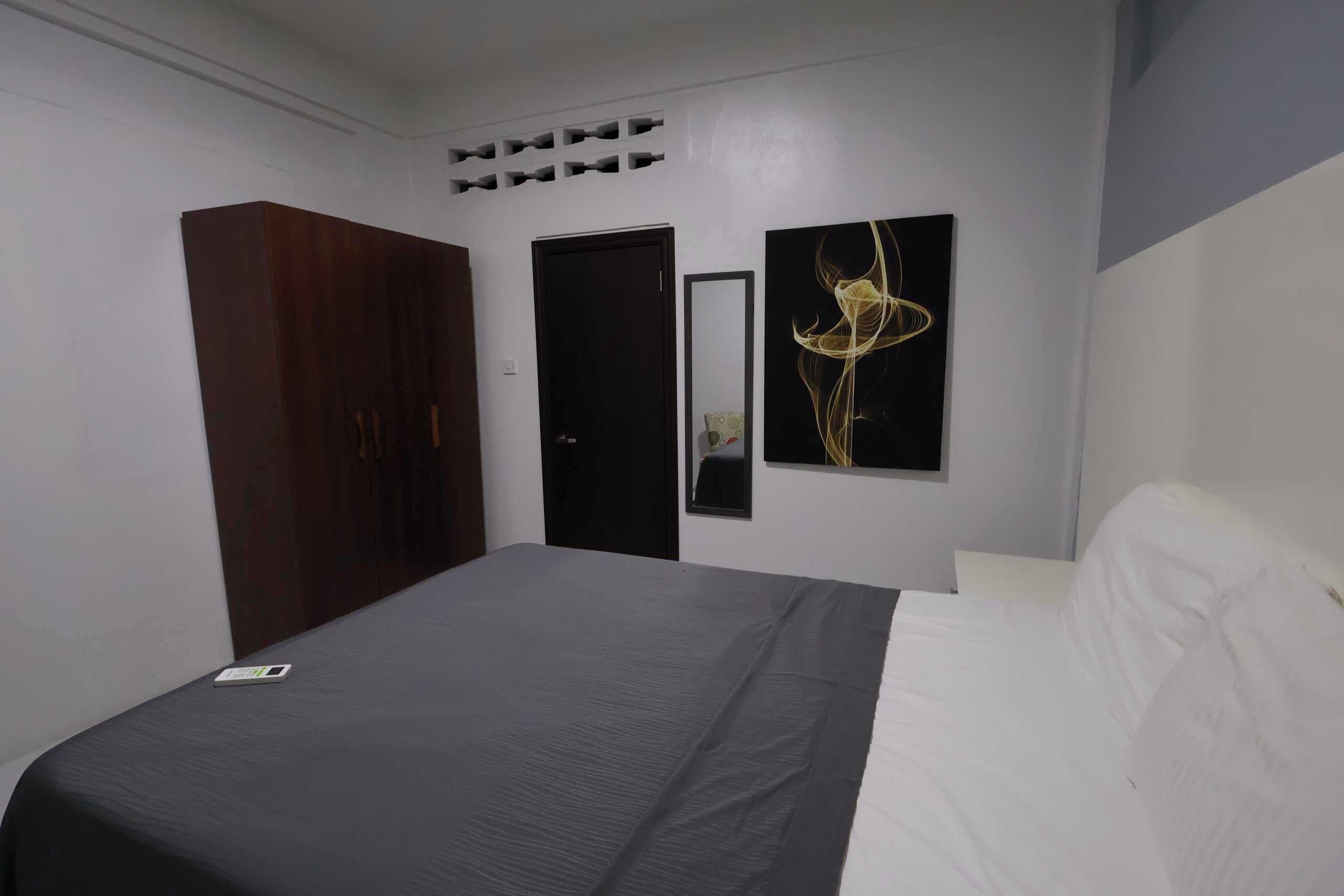 A bedroom with a bed, a wardrobe, a door, and a wall-mounted artwork.