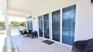 A balcony with a table and chairs, a sliding glass door, and a view of the outdoors. - PÀRIS Villas 2BD Villa Rodney Bay (Gros Islet)