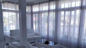 A modern living room with white furniture, large windows with sheer curtains, and a glossy tiled floor. - PÀRIS Villas 2BD Villa Rodney Bay (Gros Islet)
