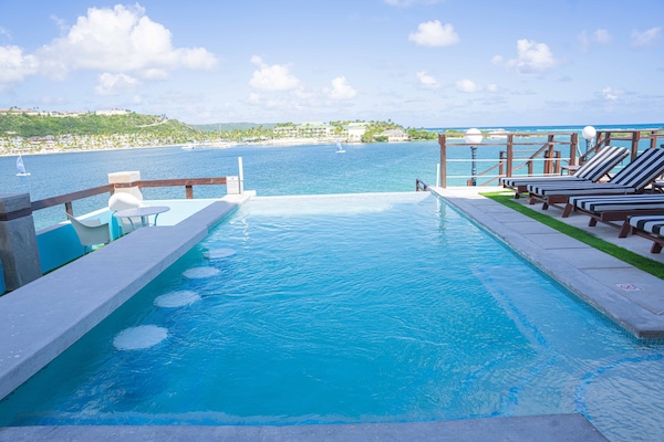 Una piscina al aire libre, sombrillas, sillones reclinables de piscina