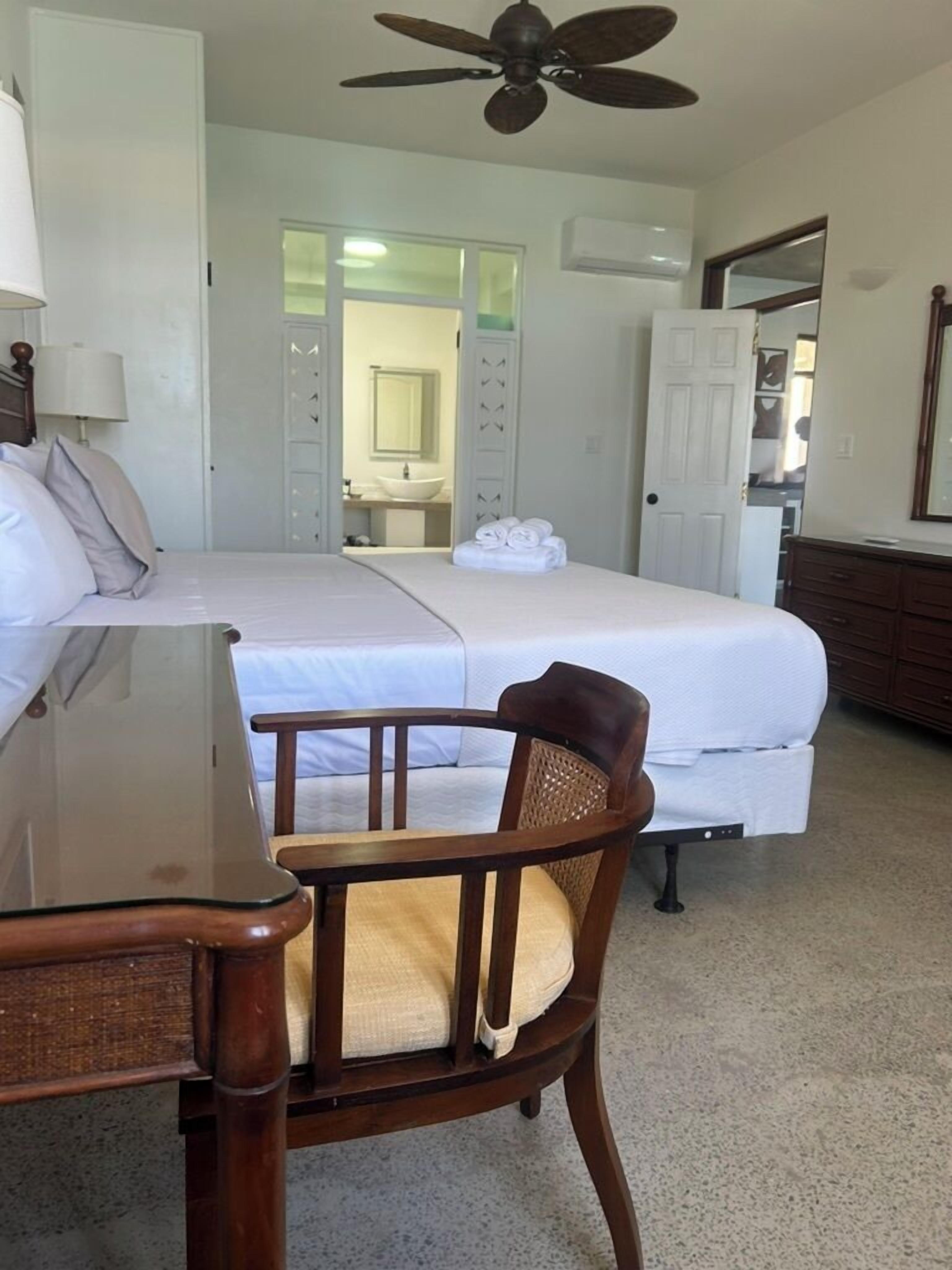 Ein Hotelzimmer mit Bett, Stuhl, Schreibtisch und Deckenventilator.