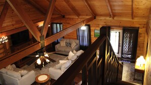 Um interior em madeira com escadas, um conjunto de sofá e uma televisão.