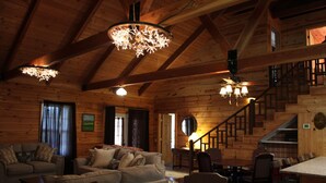 Interior espaçoso de uma cabana de madeira, com sala de estar, área de jantar e escada.