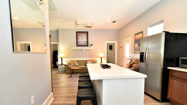 A modern kitchen with a central island, stainless steel appliances, and a seating area with a sofa and coffee table. - Teal Door Inn-With Fire Pit! (Charleston)