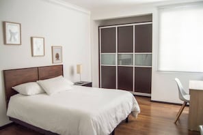 Una camera da letto con un letto, una scrivania e un armadio con ante scorrevoli.