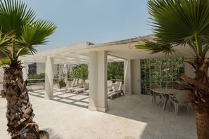 An outdoor seating area with chairs and tables, surrounded by palm trees.