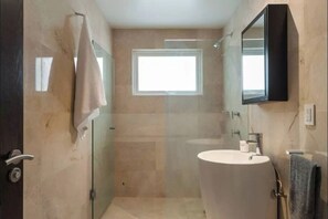Un bagno con cabina doccia in vetro, lavandino e specchio.