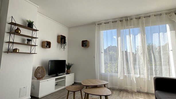 Een moderne woonkamer met een televisie, planken en een ronde tafel.