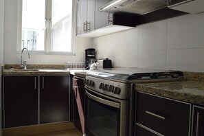 Eine Küche mit Gaskochfeld, Backofen und Kaffeemaschine.