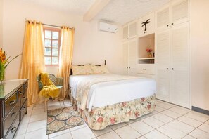 Ein Schlafzimmer mit einem Bett, einem Schminktisch, einem Stuhl, einem Fenster mit Vorhängen und einem Kleiderschrank.