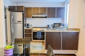 A modern kitchen with stainless steel appliances, dark wooden cabinets, and a granite countertop.