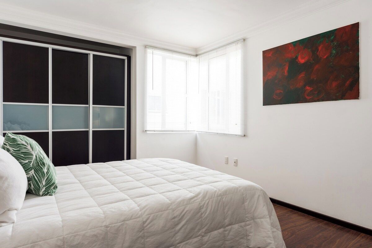 Une chambre à coucher avec un lit, une fenêtre et un tableau accroché au mur.