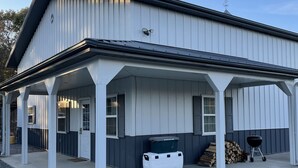 A two-story building with a covered porch, a grill, and a cooler.