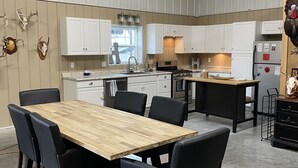 A modern kitchen with white cabinets, a wooden dining table, and black chairs.