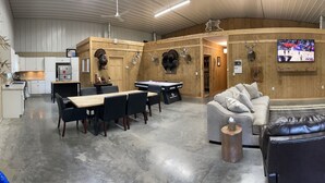 A room with a pool table, leather chairs, a sofa, and mounted animal heads on the walls.