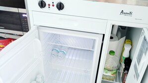 Une cuisine de taille réduite, équipée d’un réfrigérateur encastré, d’une cuisinière et d’un évier.