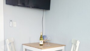 Un petit coin repas avec une table et deux chaises, une bouteille de vin et deux verres à vin.