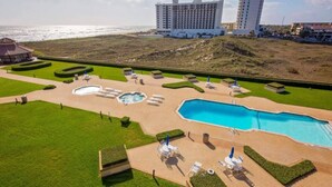 Een resort met een groot zwembad, ligbedden en uitzicht op de oceaan.