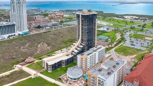 Een hoog hotel met een centrale binnenplaats, meerdere verdiepingen en uitzicht op de omgeving, inclusief een waterpartij en andere gebouwen.