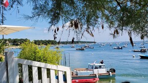 Blick auf die Küste mit einem Hafen voller Boote, einem weißen Zaun und einem Gebäude mit weißem Markisenvorbau.