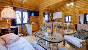 Interior acogedor de una cabaña de troncos con comedor, chimenea y sala de estar con un original centro de mesa de madera.