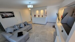 Un salon moderne avec un canapé gris, un téléviseur à écran plat et une plante décorative.