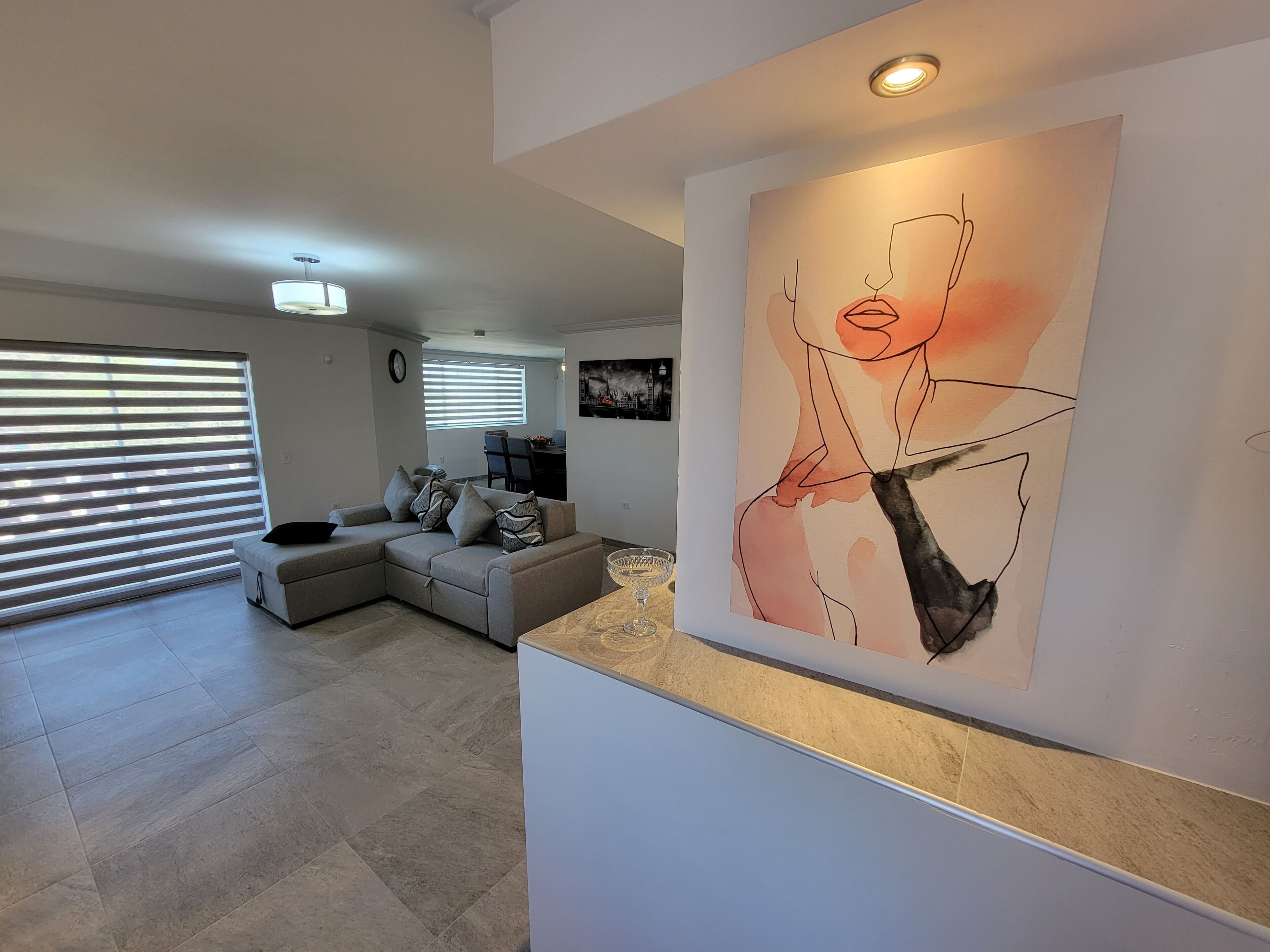 Una sala moderna con un sofá modular, un comedor y un cuadro abstracto grande en la pared.