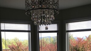 Ein Essbereich mit Tisch für zwei Personen, einer Kandelaber und großen Fenstern mit Blick auf Bäume.