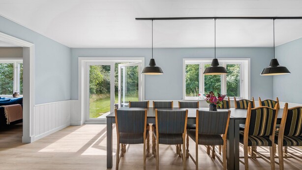 A dining area with a table and chairs, large windows, and pendant lights. - Beautiful home in Varde with kitchen (Varde)