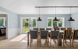 A dining area with a table and chairs, large windows, and pendant lights. - Beautiful home in Varde with kitchen (Varde)