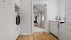 A modern kitchen with white cabinetry, a built-in washing machine, and a coffee maker. - Beautiful home in Varde with kitchen (Varde)