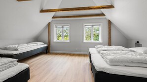 A bedroom with two beds, wooden beams, and two windows with a view of greenery. - Beautiful home in Varde with kitchen (Varde)