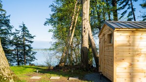 A wooden cabin with a metal roof, surrounded by trees and a lake.