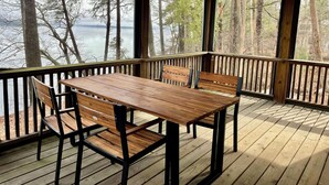 A wooden deck with a table and benches overlooking a lake and forest.