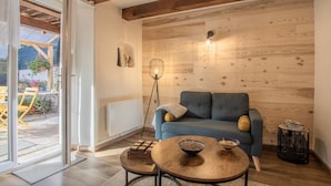 A modern living room with a wooden wall, a blue sofa, a floor lamp, and a small table with bowls. - LA Petite Maison - Bonvillard (BONVILLARD)