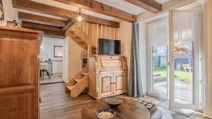 A wooden interior with a staircase, a TV, and a dining area with a table and bowls. - LA Petite Maison - Bonvillard (BONVILLARD)