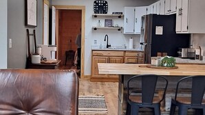 A modern kitchen with white cabinets, a central island, and bar stools. - LakeWay II- 4 min from US-41 and Lake Sullivan (Sullivan)