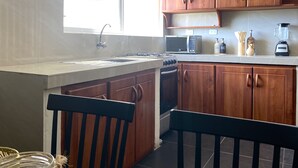 A kitchen with wooden cabinets, a stove, a microwave, and a sink.