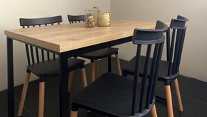 A dining table with six chairs, two glass jars with cork stoppers, and a decorative golden object.