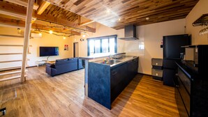 Una cocina moderna con suelo de madera, una isla central, electrodomésticos integrados y un amplio ventanal que proporciona luz natural.