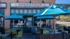 Una cafetería llamada SPEEDTRAP con mesas al aire libre y sombrillas verdes.